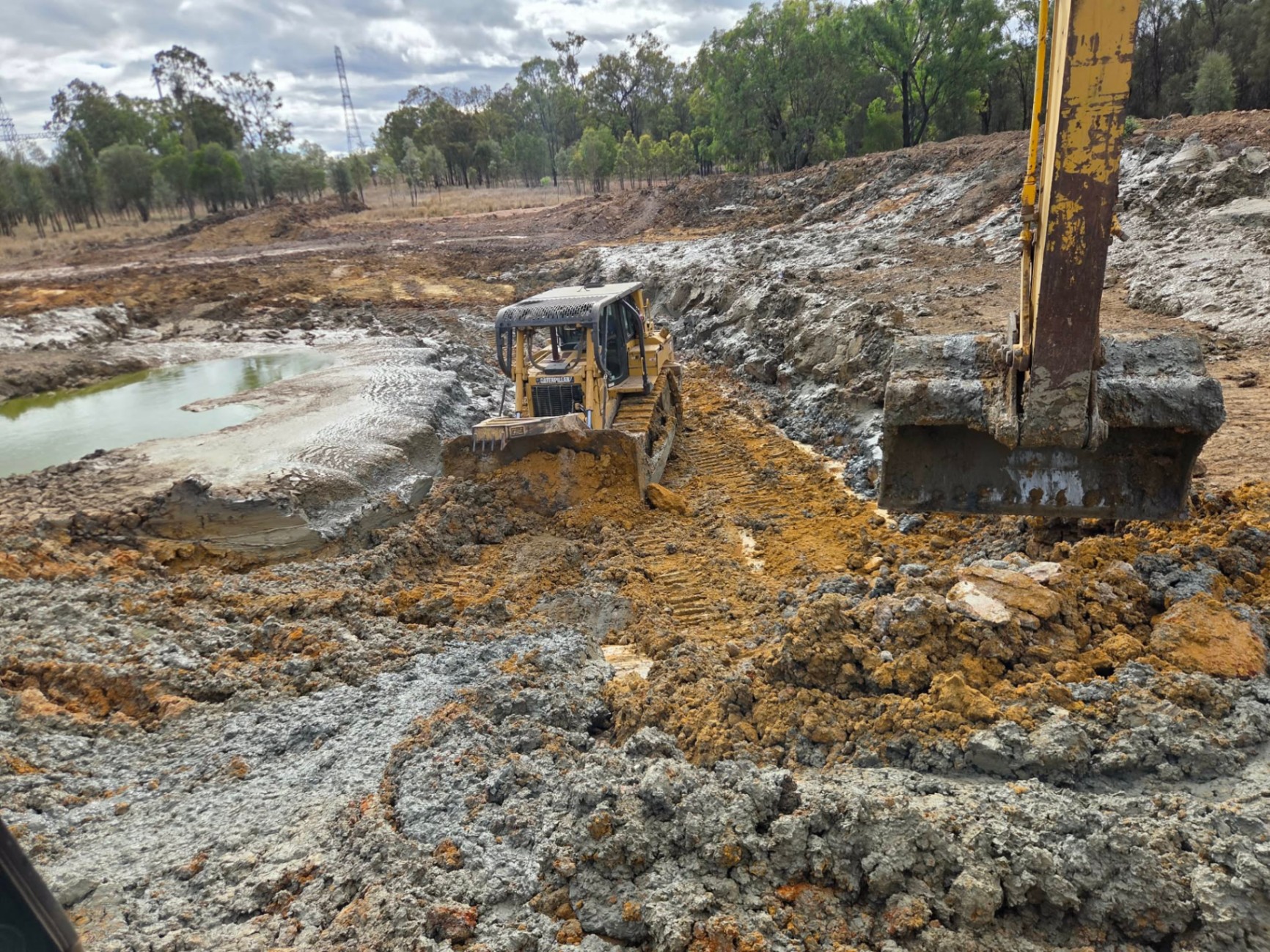 CAT D6T dozer pushing wet mud on a new dam construction job