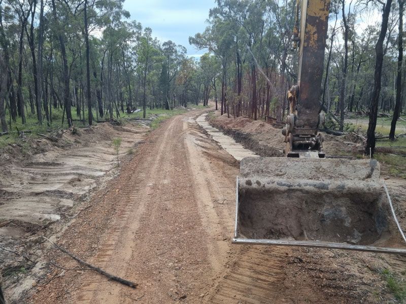 Excavator forming a new bush access track with table drains